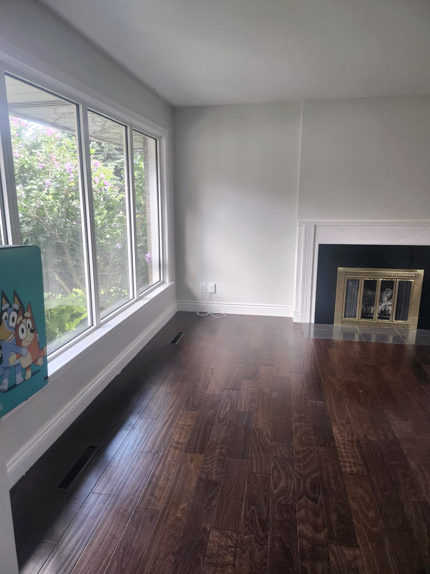 Empty living room with gleaming hardwood floors and clean windows